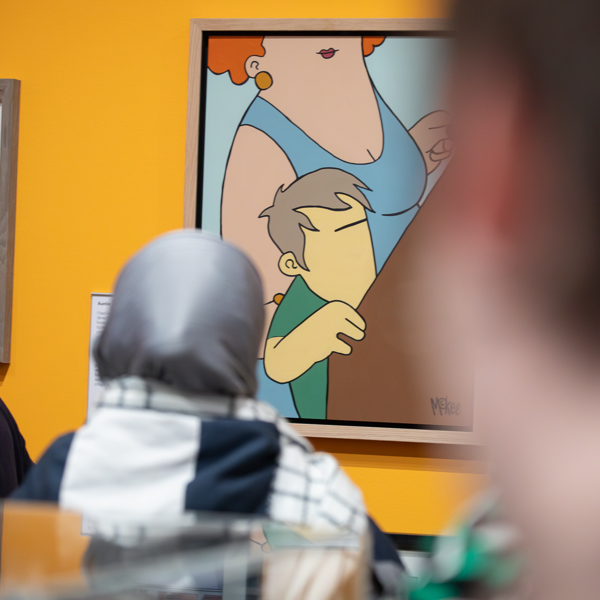 A person looks at a colourful paiaiting of a woman and a young boy