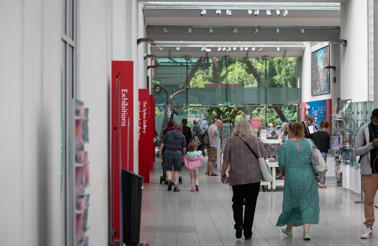 Adults and a child walking through the Millennium Gallery shop and entrance / exit to the Winter Gardens.  