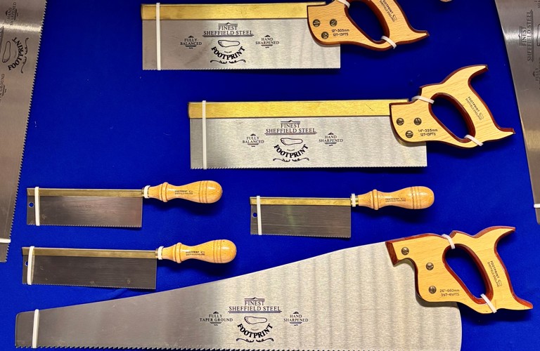 A photograph showing a collection of saws from the Hawley Collection at Kelham Island Museum. They are photographed against a blue background