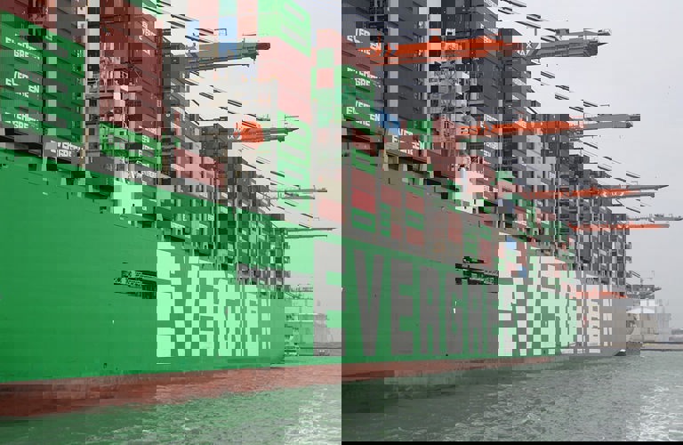 A large cargo ship, loaded with shipping containers, docked at a port. 