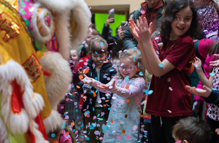 Children in a museum smiling while being showered by confetti