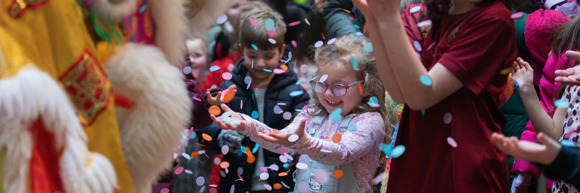 Children in a museum smiling while being showered by confetti