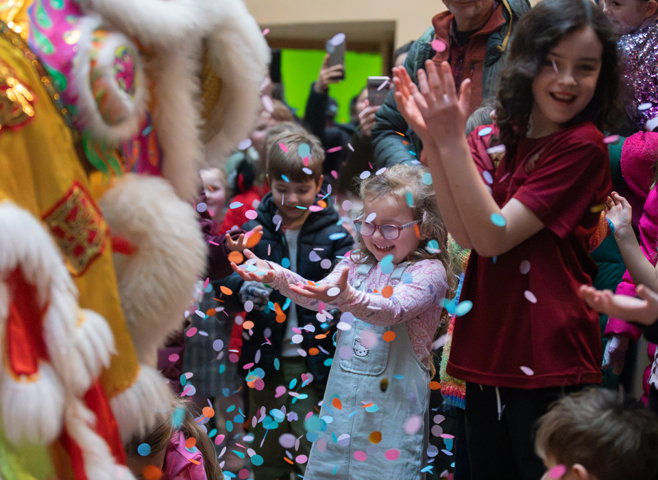 Children in a museum smiling while being showered by confetti
