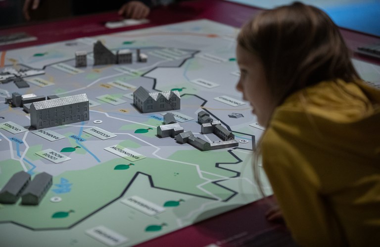 A child looking at an illustrated map of Sheffield with model buildings placed on it. 