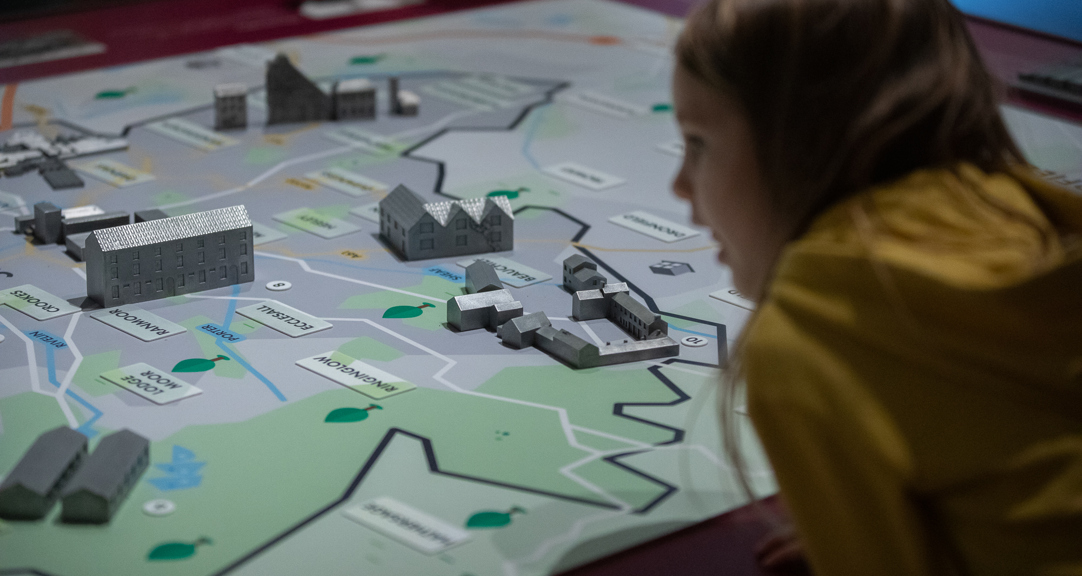 A child looking at an illustrated map of Sheffield with model buildings placed on it. 