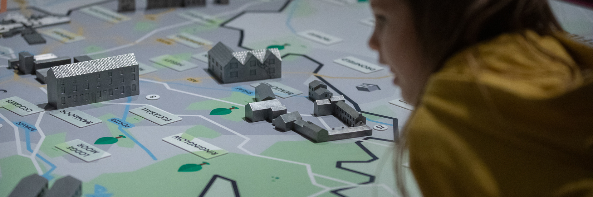 A child looking at an illustrated map of Sheffield with model buildings placed on it. 
