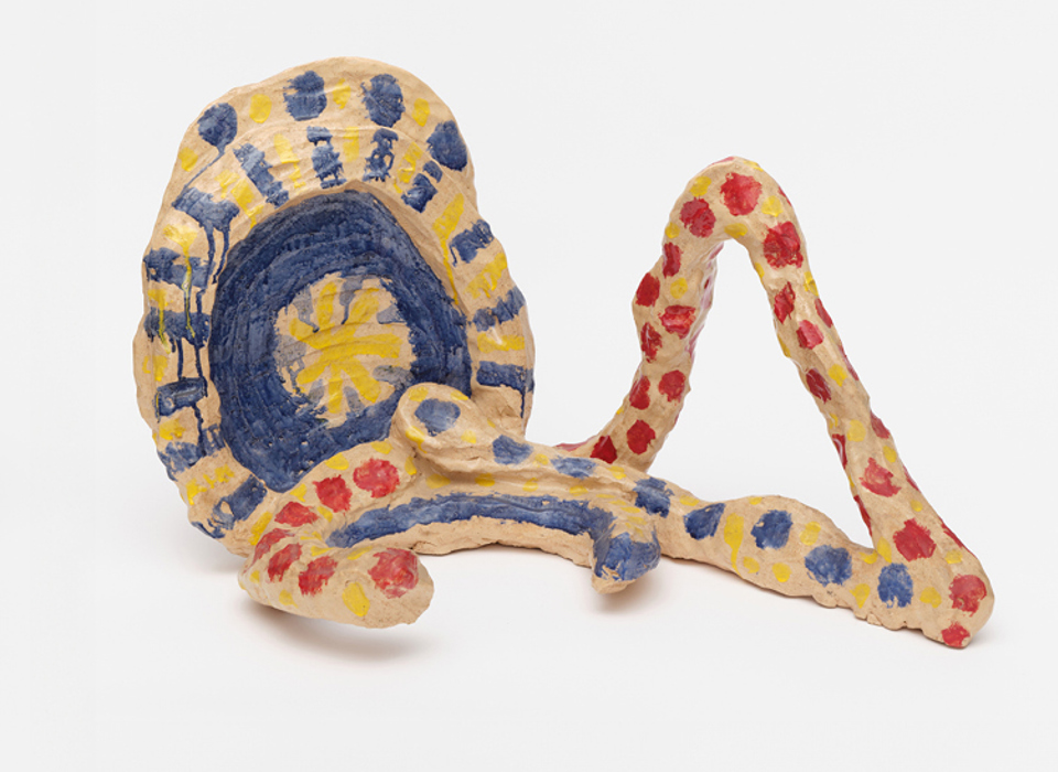 A composite image showing three works of ceramic sculpture by John Hoyland, all shown on a white background. The first sculpture (on the left of the image) is called The World. It is comprised of a black globe shape resting on a flared blue pedestal. A smaller yellow globe is attached to the upper left of the black globe, a black horn protrudes from the top, and a curved brown shape comes out of of the left side of the globe. Splashes of yellow, pink and black paint adorn the whole piece.

In the centre is Hoyland's work Thupelo Memory. A pink, yellow and blue painted triangle shape rests a top a pink, oval shaped base. A pink curved shape rests behind it, snaking up to the top of the triangle. Behind that is a large pink circle shape, with a line through it. All are decorated with splodges of red and burgundy paint.

On the right is John Hoyland's work The King. A large oval shape stands on the left side of the work, painted blue with a yellow star in the centre, then blue and yellow stripes along on the outer edge. A red and blue spotted snake shape adjoins it, with one side forming into a large triangle shape. 