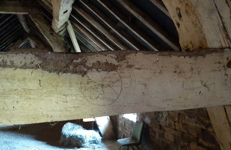 A photograph of a roof beam in a building. On the roof beam there are marks and symbols.   