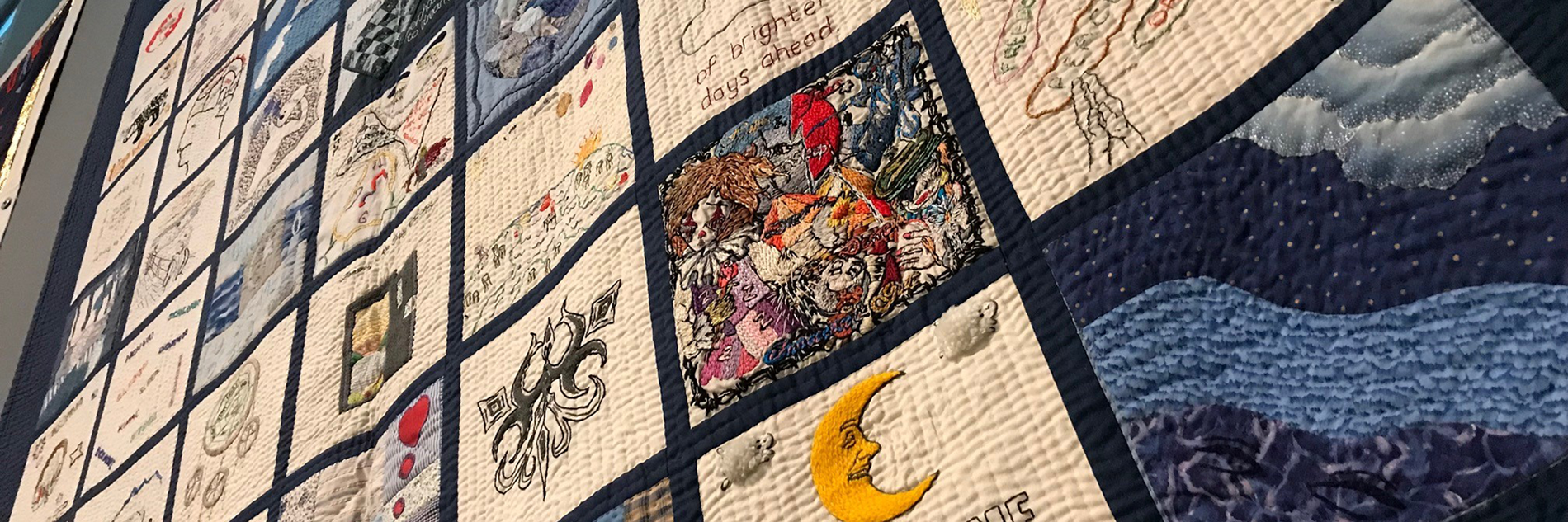 A large embroidered quilt, featuring patches with different designs.