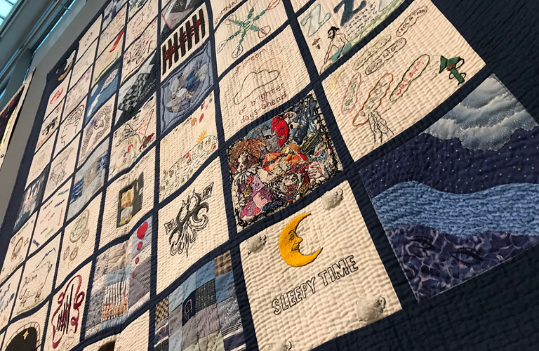 A large embroidered quilt, featuring patches with different designs.