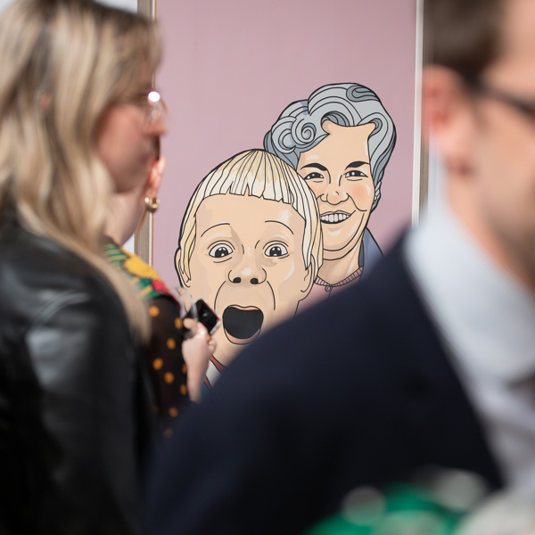 Visitors in front of a colourful painting of a child and a smiling woman in an art gallery
