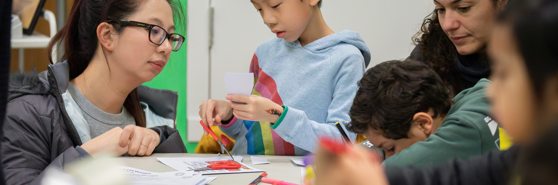 A mother-figure and child concentrating on cutting and sticking.