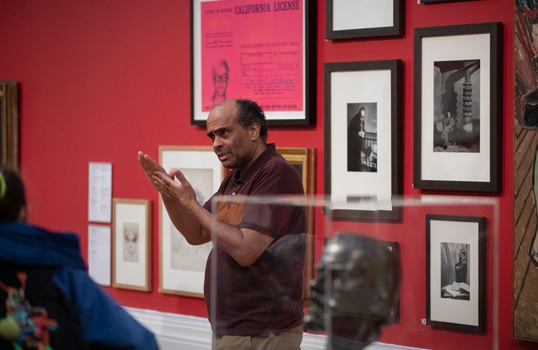An adult giving a tour of an art gallery, using British Sign Language.