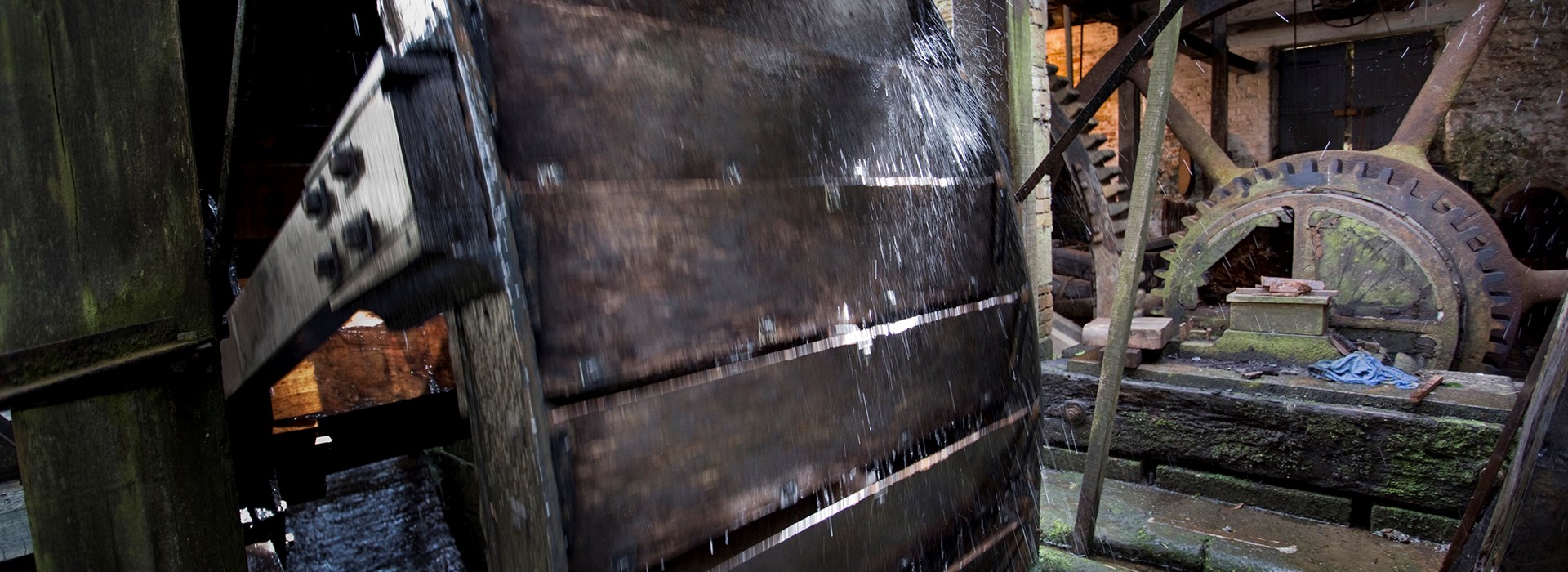 Detail of a water powered wheel with toothed flywheel in the background