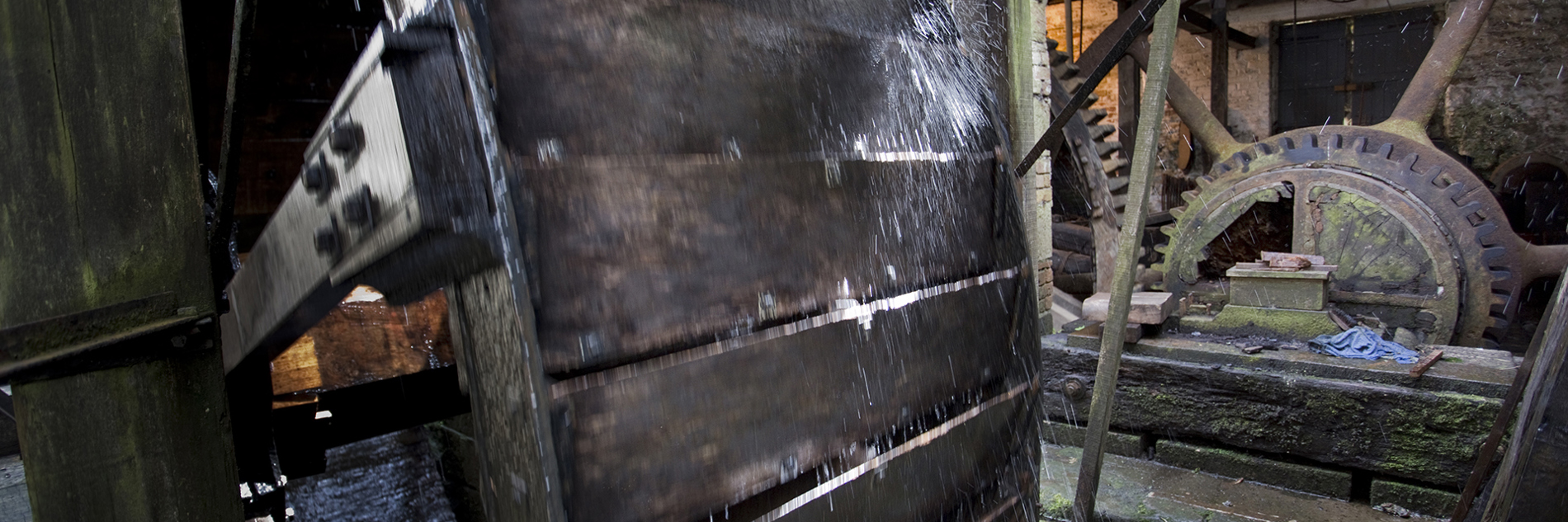 Detail of a water powered wheel with toothed flywheel in the background