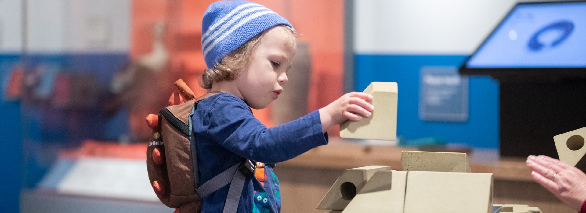 A child holding a white building brick in a museum gallery 