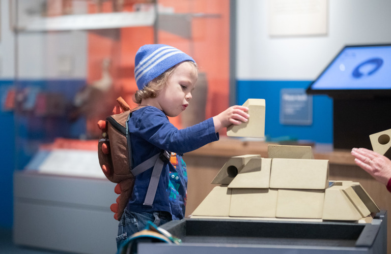 A child holding a white building brick in a museum gallery 