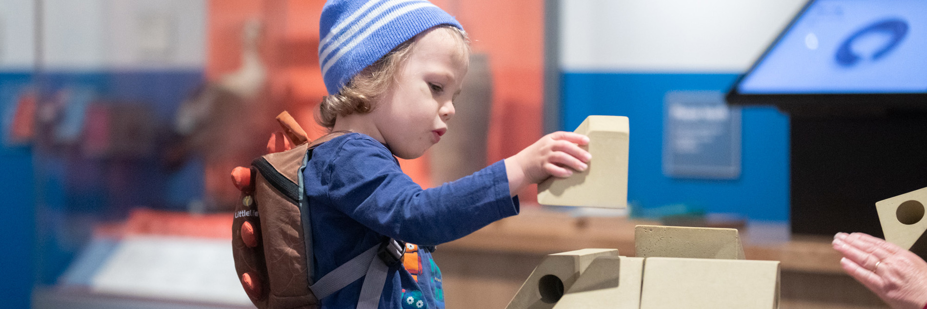A child holding a white building brick in a museum gallery 