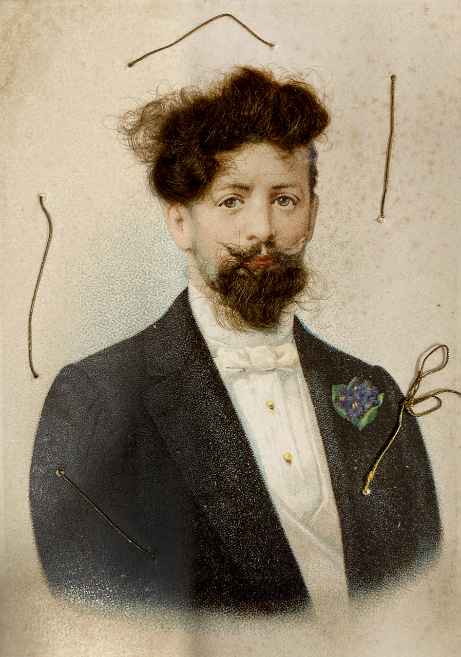 A postcard featuring an illustrated portrait of a Victorian-looking man who is wearing a formal shirt and dinner jacket with a floral buttonhole. Real hair has been stuck onto the card to depict his hair and beard.  