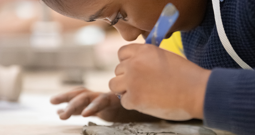  A close up photograph of a child mark making on clay. 