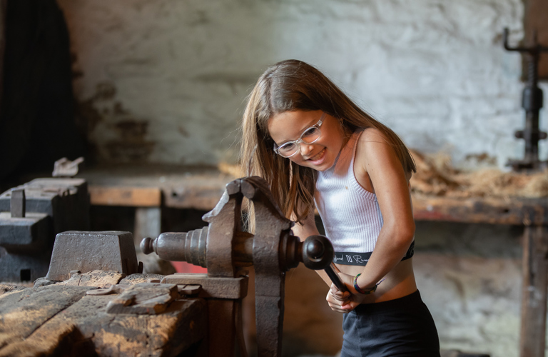 A young visitor tries a historic bench vice at Abbeydale Industrial Hamlet.