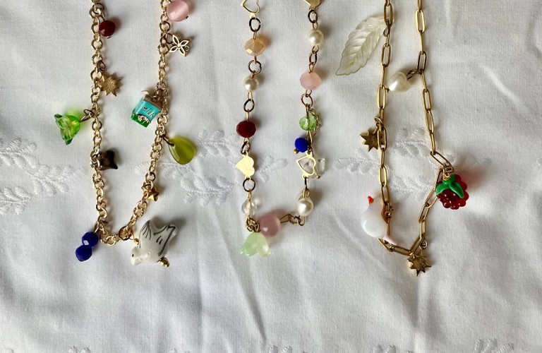 A photograph of three gold charm necklaces with various little charms on