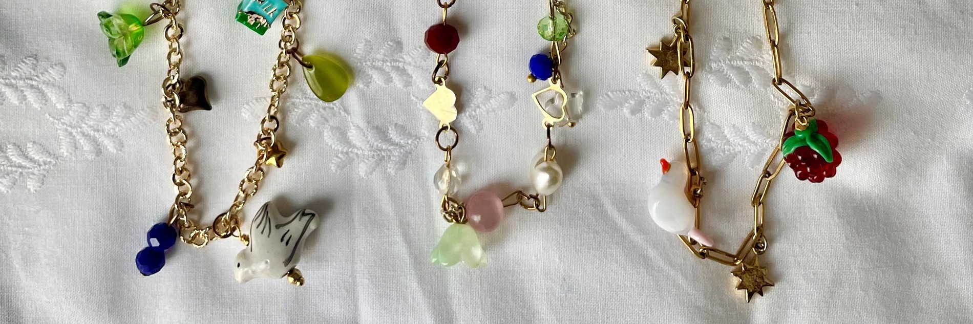 A photograph of three gold charm necklaces with various little charms on