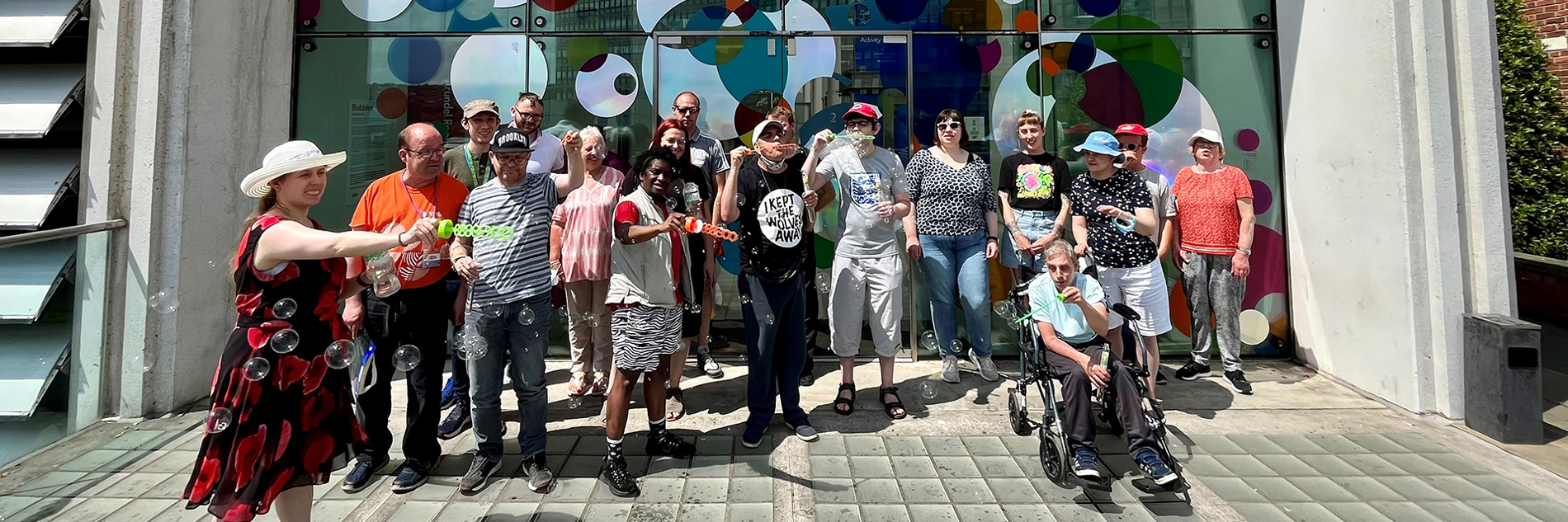 A group of adults in front of a large colourful artwork at the Millennium Gallery 
