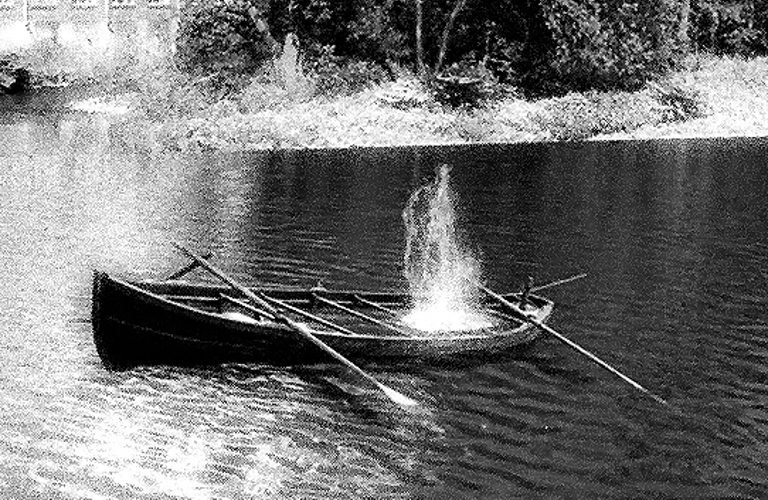 A black and white photograph of a canoe and oars in water.  