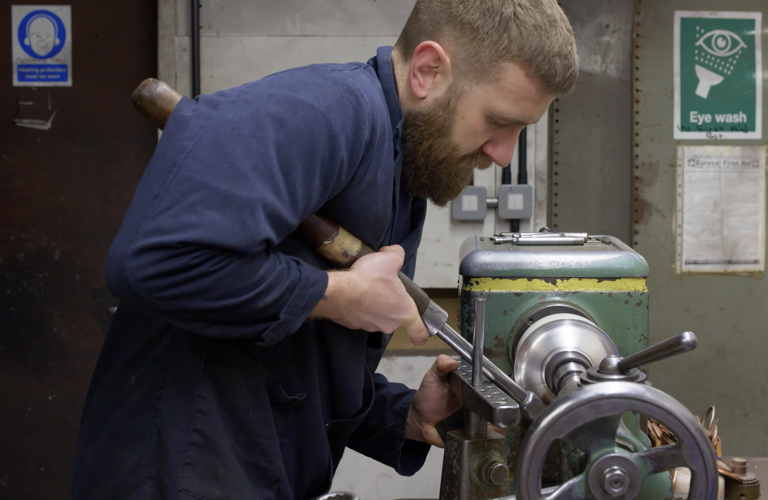 A photograph of an adult in a workshop using a piece of machinery. 