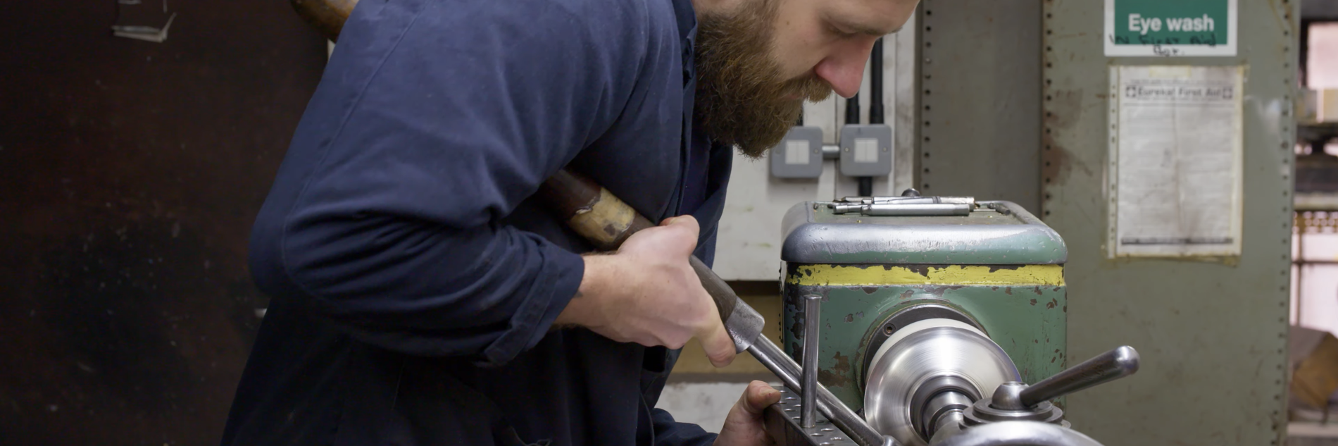 A photograph of an adult in a workshop using a piece of machinery. 