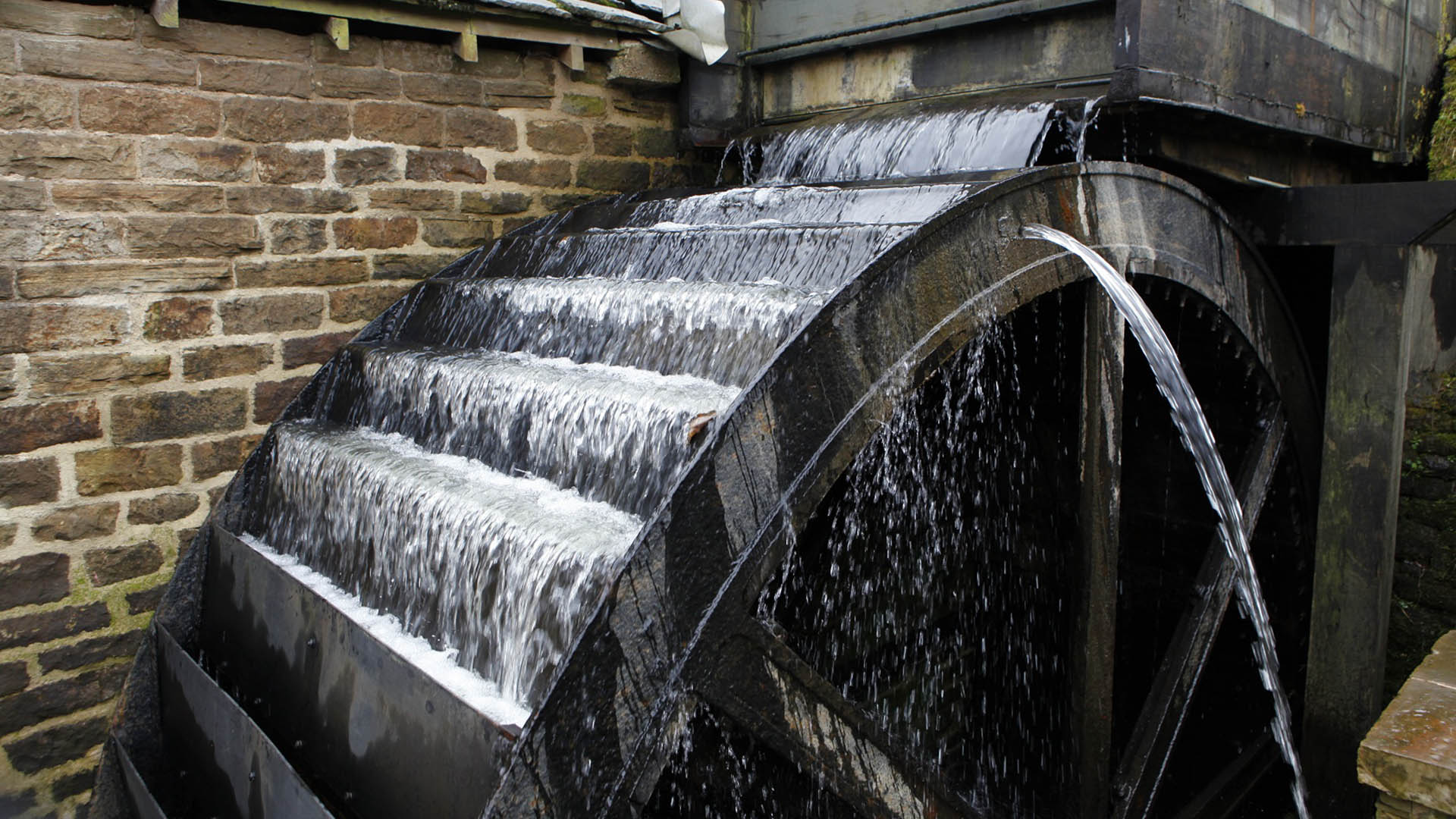 Close up of overshot waterwheel turning as it fills with running water.
