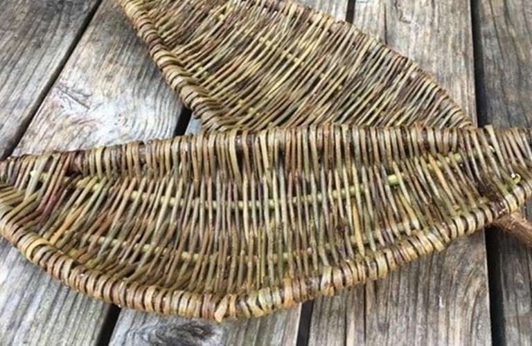 A photograph of two handwoven leaf shaped willow panels. They are placed on wooden slats.
