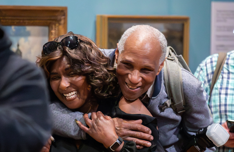 Two people hugging and smiling in front of museum displays