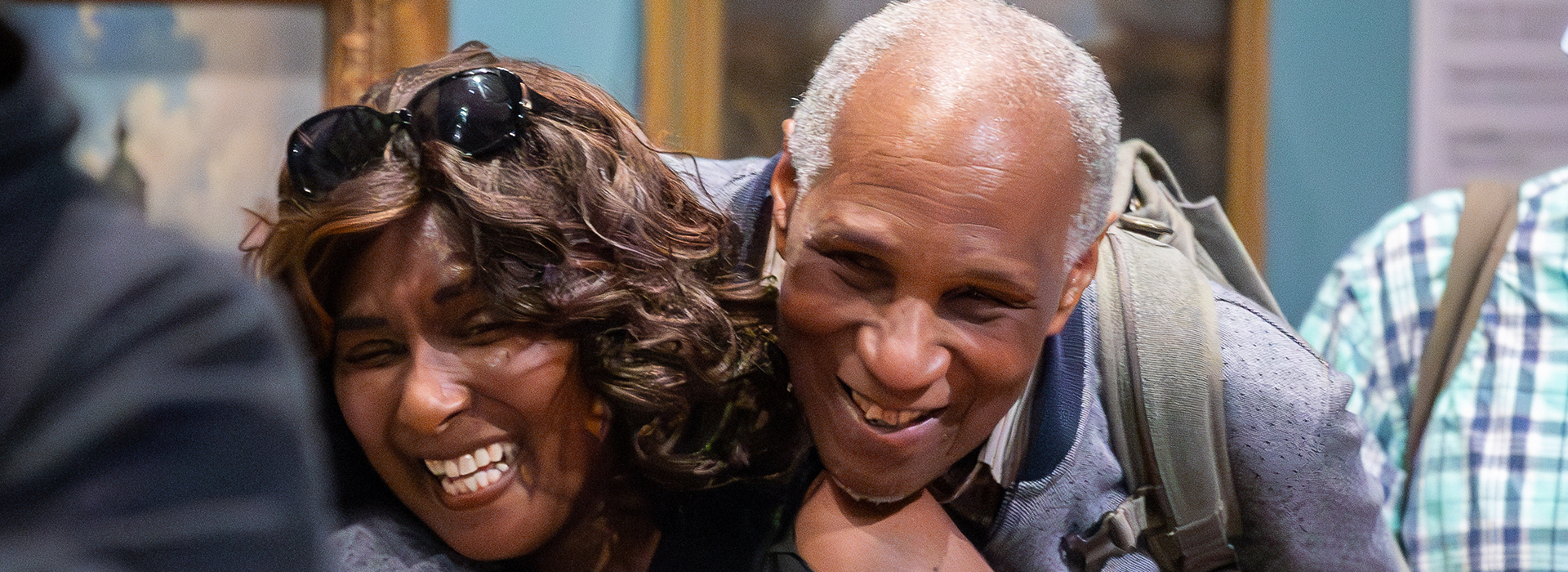 Two people hugging and smiling in front of museum displays