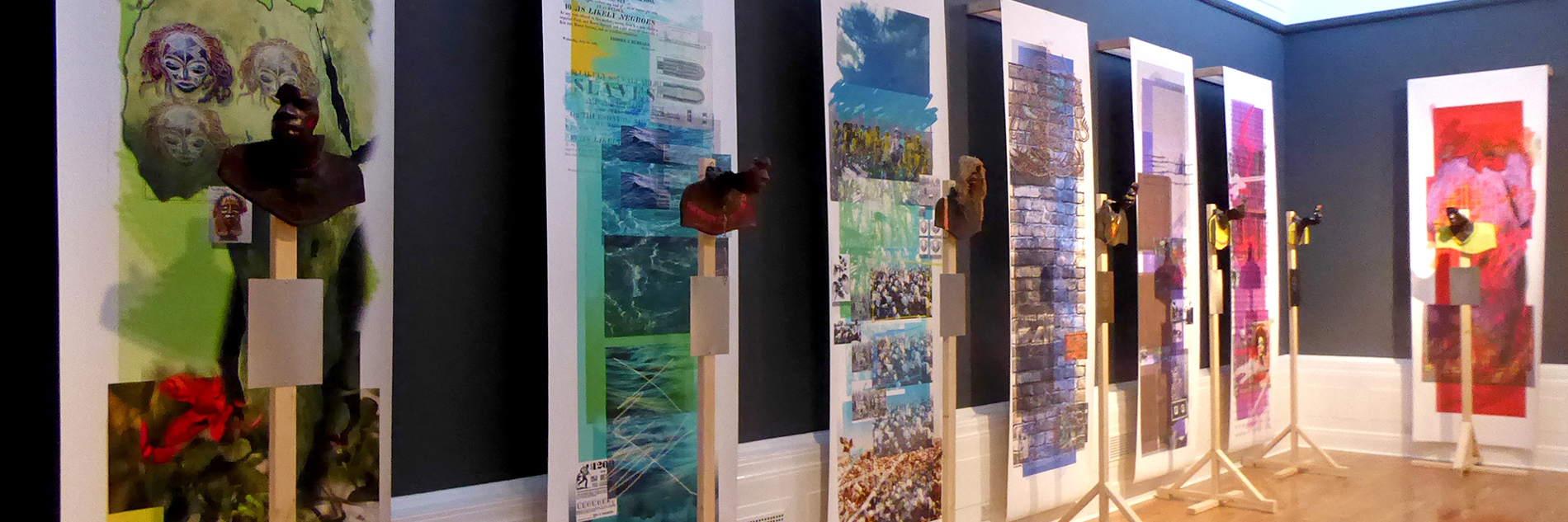 A series of seven hanging, horizontal colourful collages. Each collage has different images from faces to landscapes and brickwork. In front of each collage is a partial sculpture of a head 