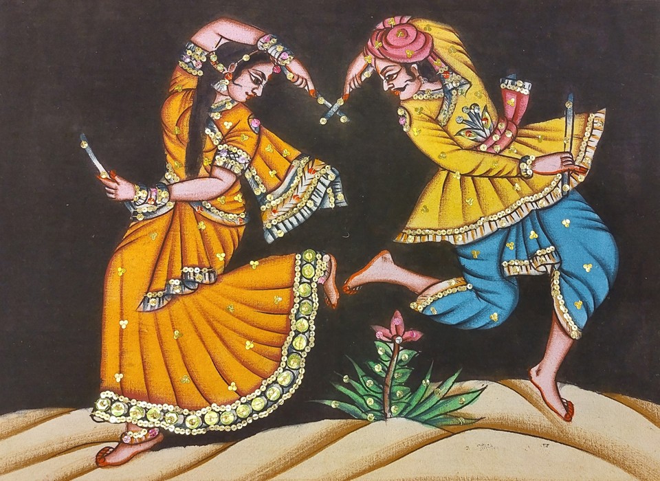 A photograph of an Indian fabric artworks depicting two dancers, one male and one female, both dressed in yellow outfits. The man also wears blue trousers. Both are barefoot and looking at each other.