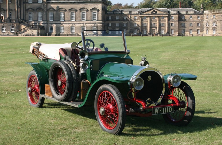 A photograph of one of Sheffield Museum's Simplex cars, with a green body and red wheels. Is it photographed on the green lawn outside of Wentworth Woodhouse, a stately home in South Yorkshire.