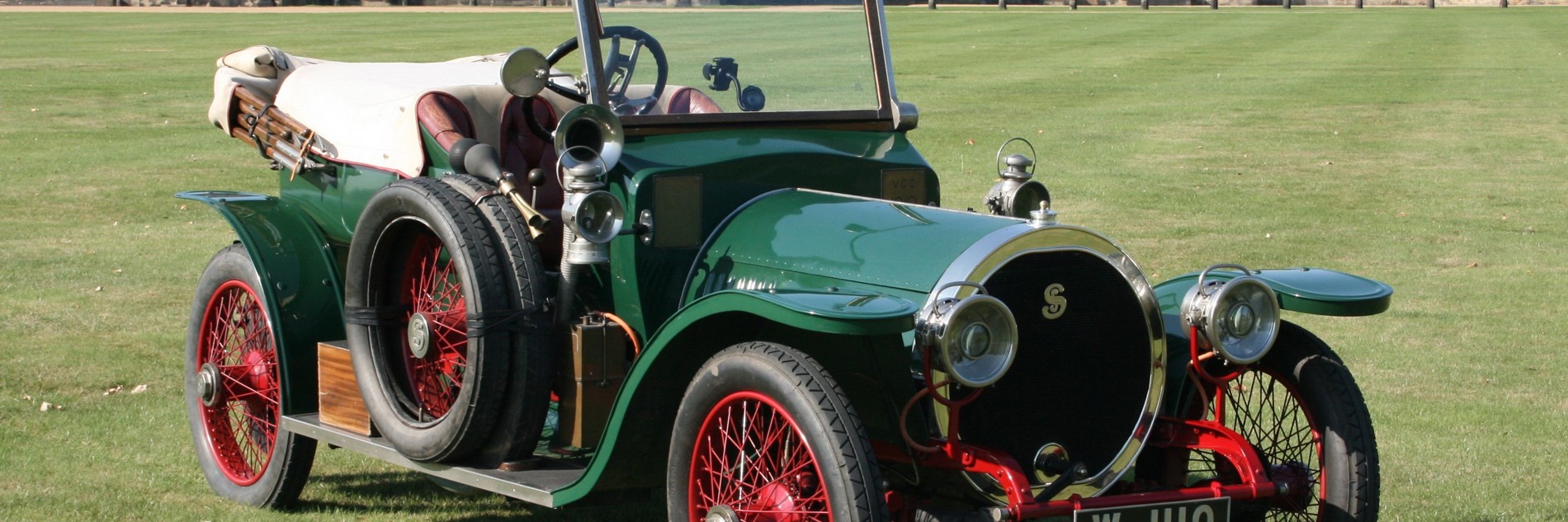 A photograph of one of Sheffield Museum's Simplex cars, with a green body and red wheels. Is it photographed on the green lawn outside of Wentworth Woodhouse, a stately home in South Yorkshire.