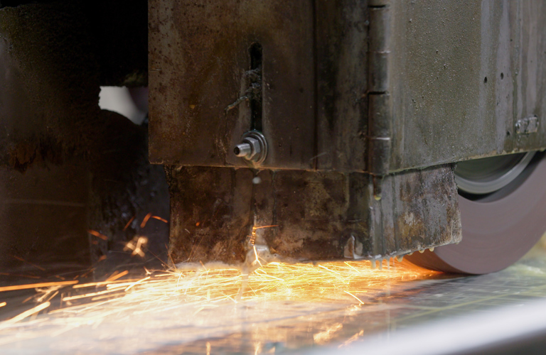 A photograph of machinery on wheels running down a track and creating orange and yellow sparks.  