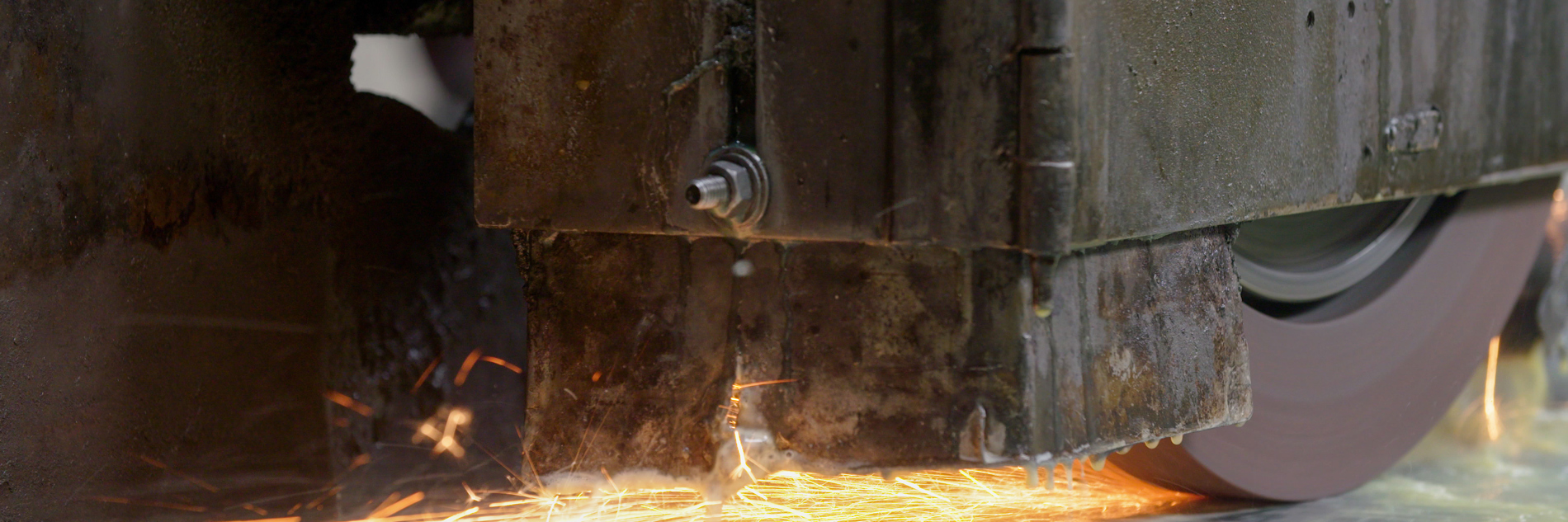 A photograph of machinery on wheels running down a track and creating orange and yellow sparks.  