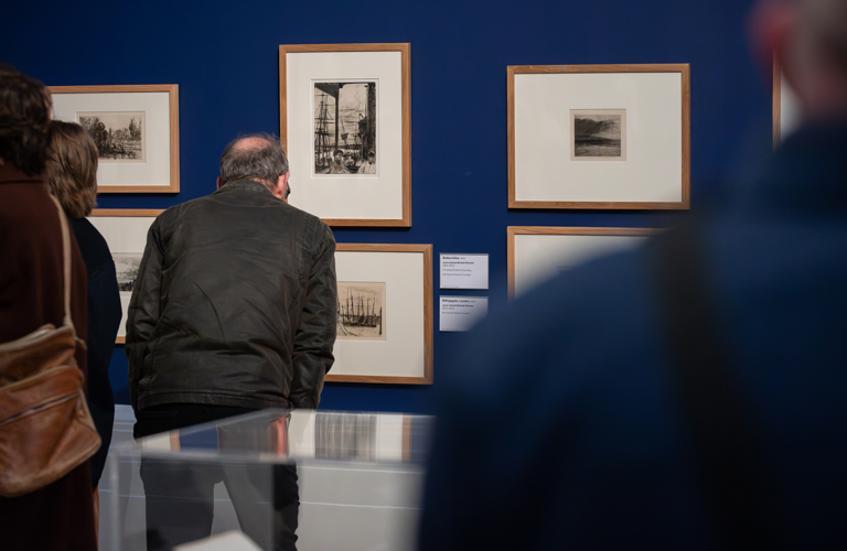 A photograph of adults looking at artworks in a gallery. 