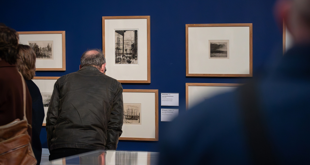 A photograph of adults looking at artworks in a gallery. 
