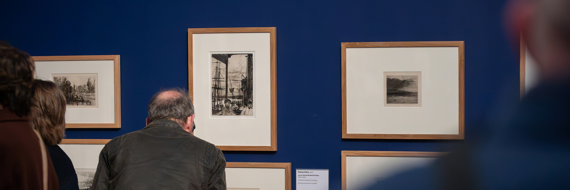 A photograph of adults looking at artworks in a gallery. 